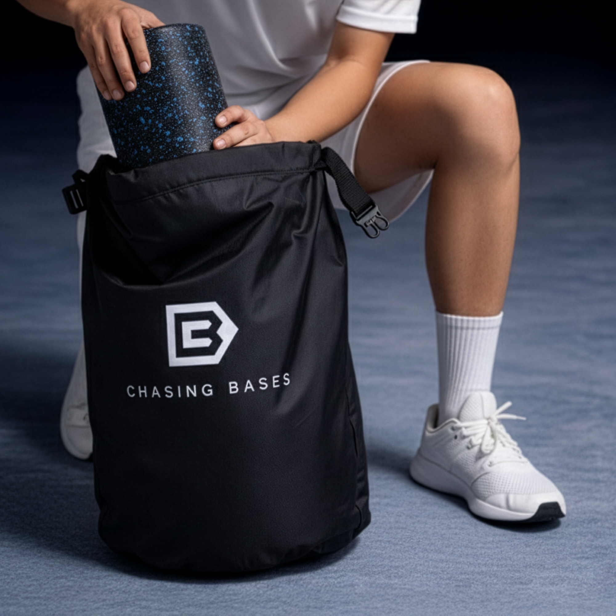 Athlete holding a black bag with 'Chasing Bases' logo on a dark blue background